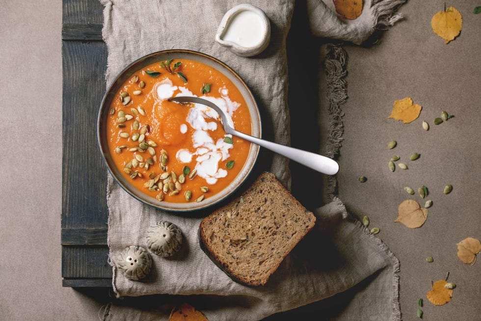 pumpkin soup with cream and seeds in ceramic bowl on linen cloth