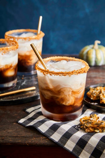 pumpkin spice white russian cocktails in glasses rimmed with gingersnap crumbs, served with pumpkin seed brittle