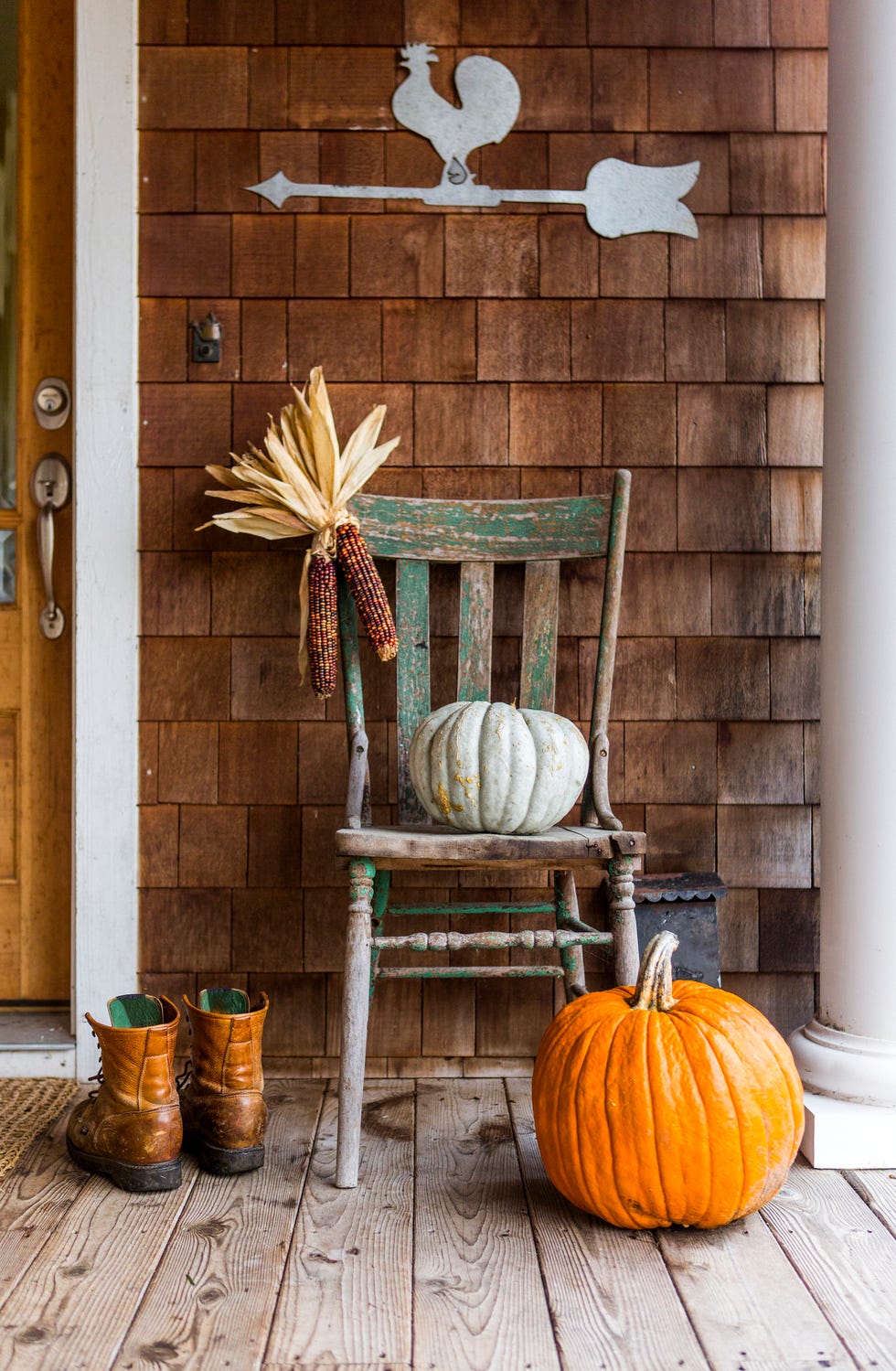 fall porch decor, pumpkins and corn on distressed wood chair on porch with boots in autumn