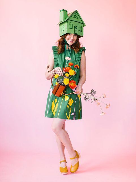 green house pun costume with green house shaped paper hat, green floral dress, and watering can filled with flowers