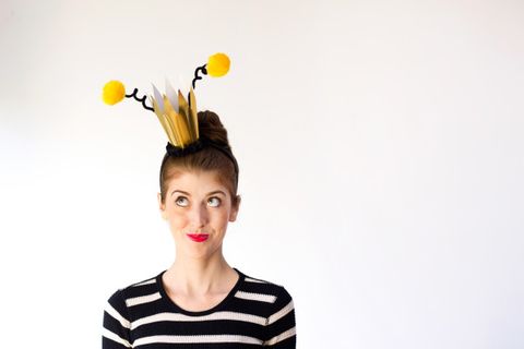 queen bee women's pun costume with gold crown and bee antennae headpiece and black striped top