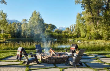 stone firepit surrounded by adirondack chairs