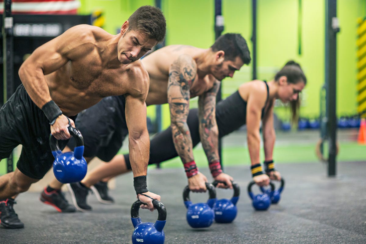 Group, workout and dumbbell push up at gym for muscle, power or strength.  Teamwork, sports or energy of people, athletes or bodybuilder friends  exercise or training at fitness center for healthcare. Stock