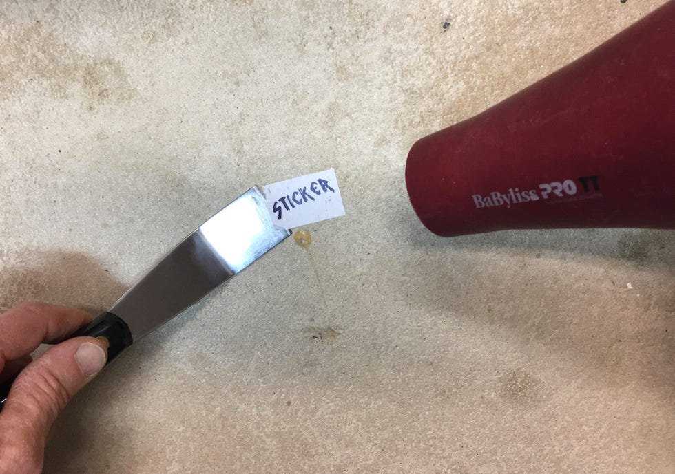 putty knife and hair dryer being used to remove a sticker