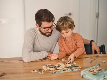 niño y padre haciendo puzzle en una mesa