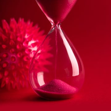 hourglass with red sand next to red germ microbe on red background viruses infection