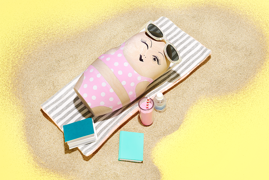 round doll lying on beach towel with smoothie