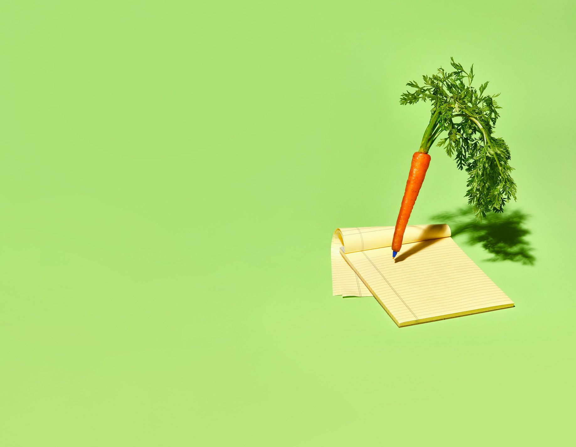 carrot pen and notepad visual metaphor for signing a pledge to go vegan food diary