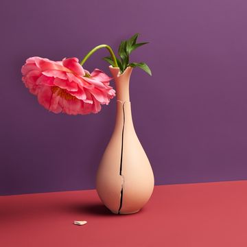 dying pink flower in cracked, ceramic vase