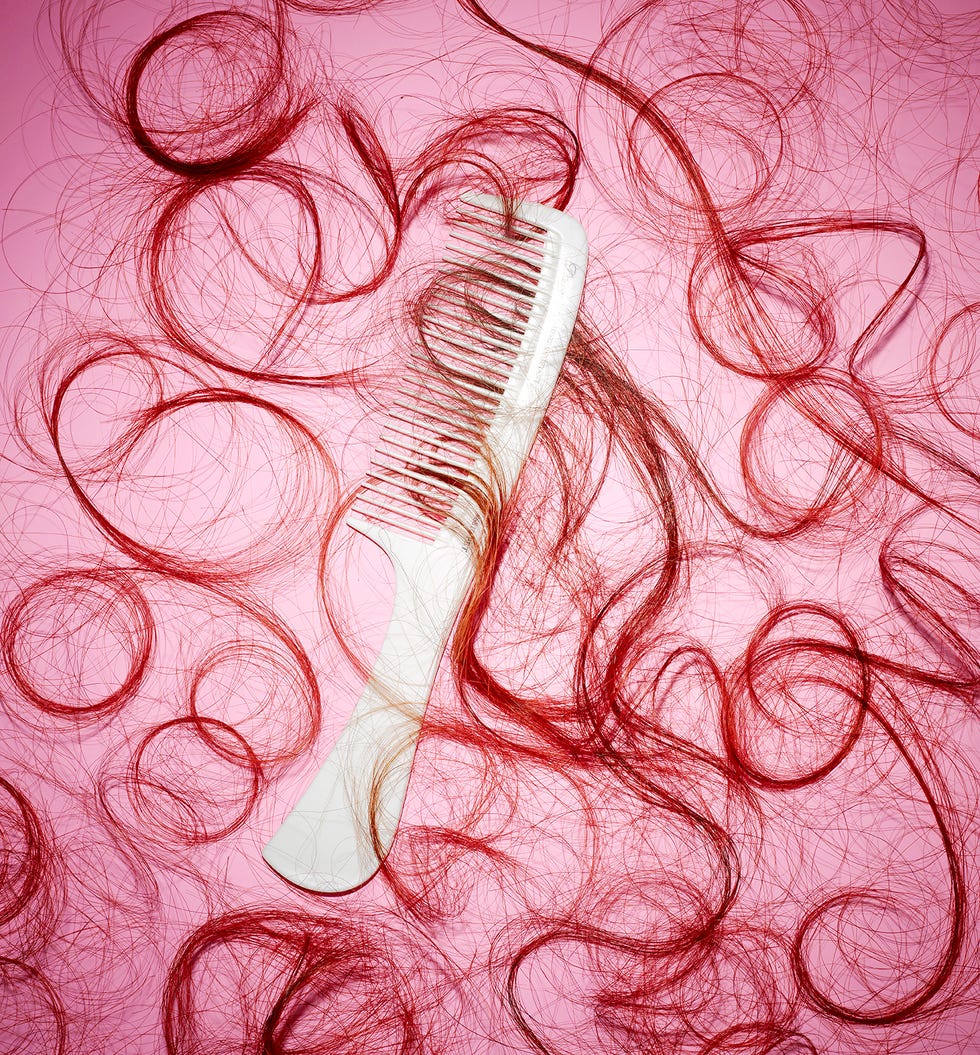 red hair cuttings on pink background with white comb