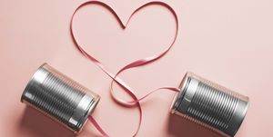 tin can telephones on a pink background with a heart shaped cord connecting them