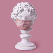 gypsum antique statue of boy's head in protective mask anti infection from respiratory sick on a light pink background with copy space outbreak of coronavirus concept