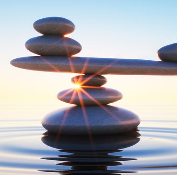 stack of stones in calm water with seesaw in the evening sun