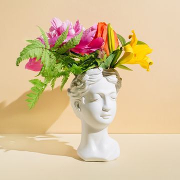 white marble head sculpture with flowers on beige background