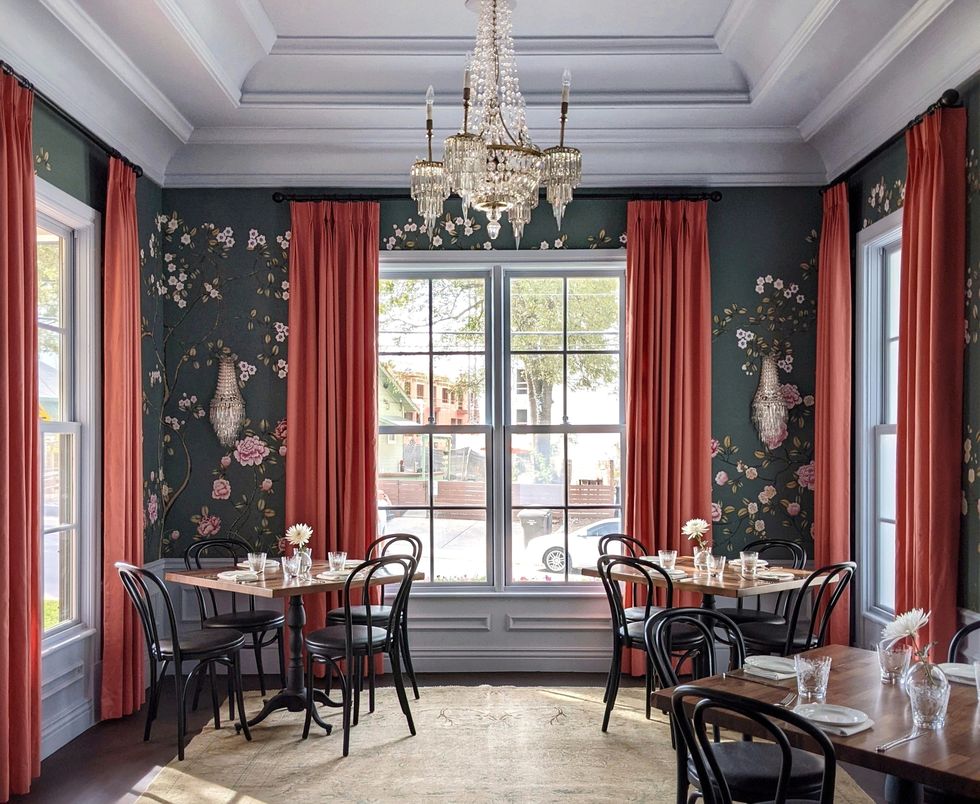dining room with large window, salmon curtains, gray floral walls