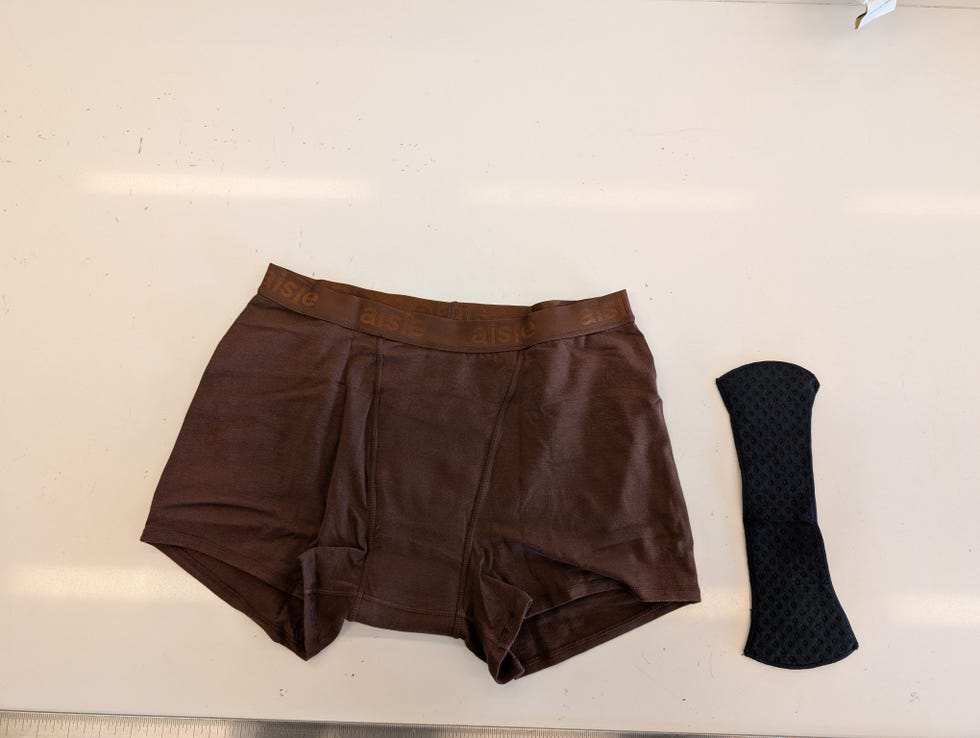 a pair of brown aisle boxer shorts with a removable pad next to it, good housekeeping's testing for the best period underwear