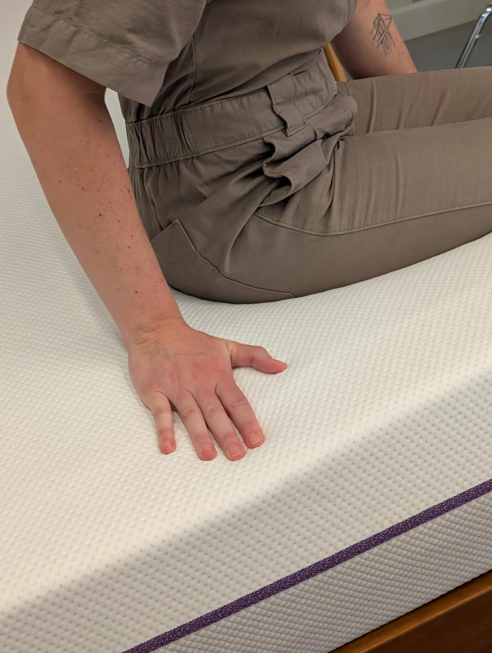 a person sitting on a mattress to check the firmness