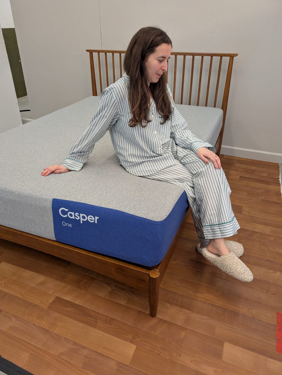 a person seated on a casper mattress in a bedroom setting