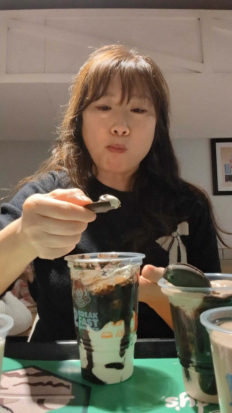wendy's thin mint frosty a person scooping up the dessert with a thin mint cookie