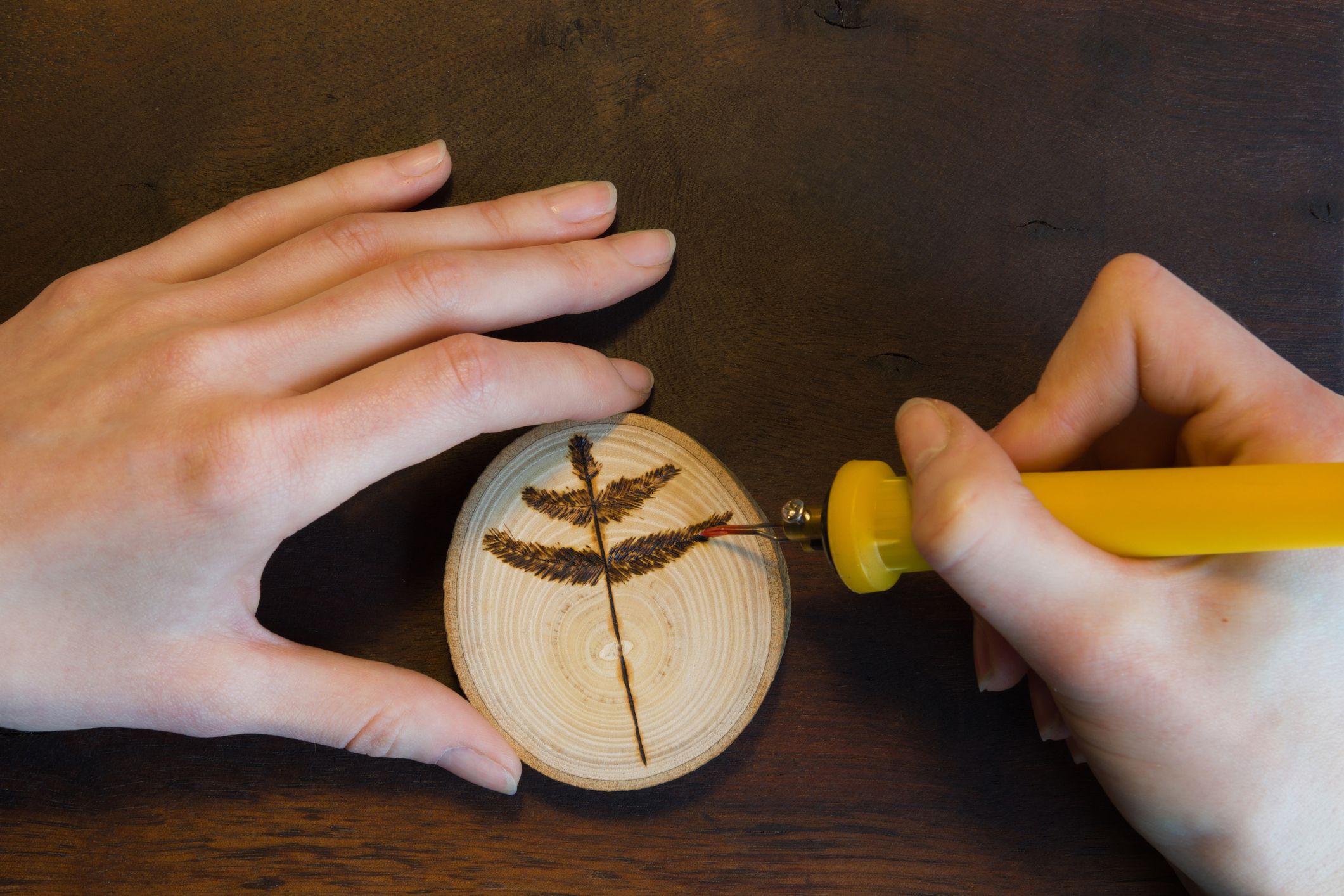 Person Holding a Wood Burning Tool, Burning Letters onto Wood Stock Photo