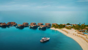 overwater bungalows with a yacht in a tranquil blue sea