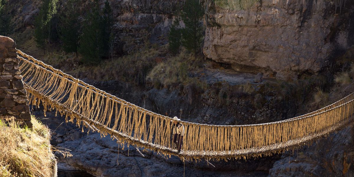 Een Quechuaman loopt over de oude hangbrug voor de ceremonie begint