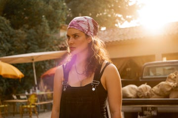 person standing outdoors with a truck and bags in the background during sunset
