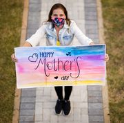 quarantine mothers day ideas woman holding up a happy mother's day sign
