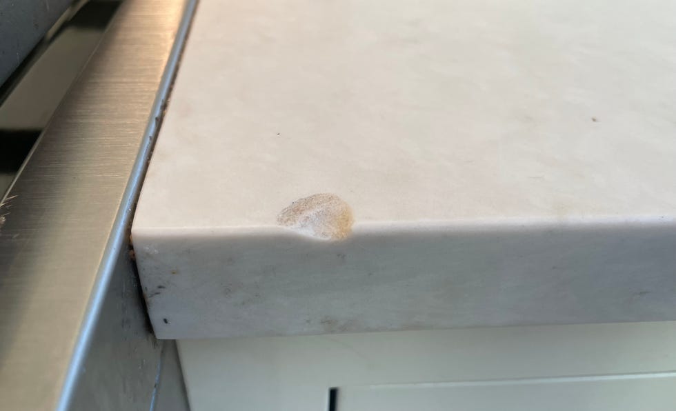 a quartz countertop with a chip in its edge, likely caused by a heavy cast iron pan