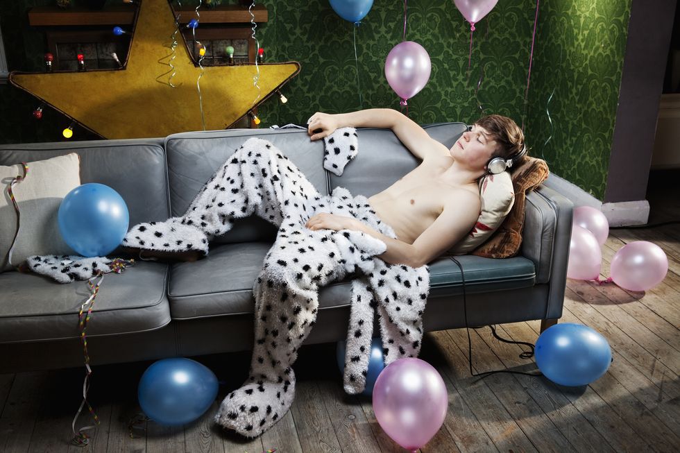 hombre joven disfrazado tras una noche de fiesta duerme en el sofá