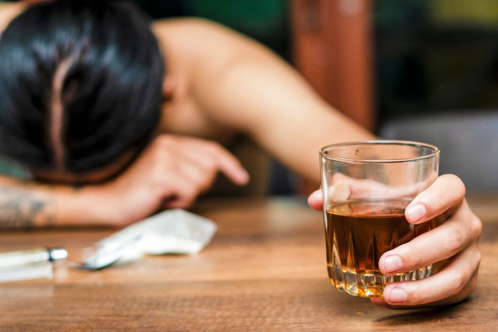 mujer bebida apoya la cabeza sobre la mesa con una copa en la mano