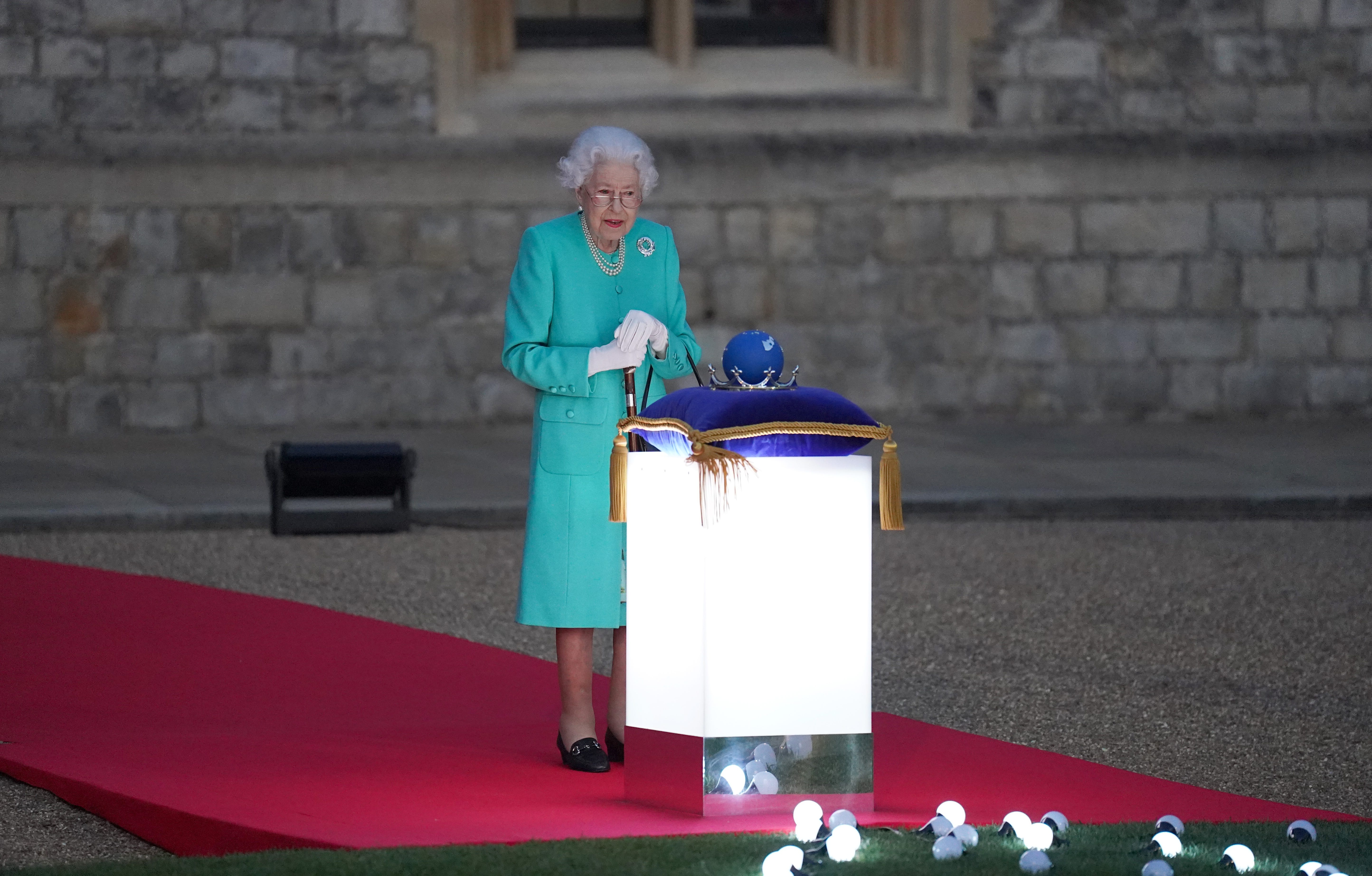 windsor, england   june 02 britains queen elizabeth ii prepares to touch the commonwealth nations globe to start the lighting of the principal beacon outside of buckingham palace in london, from the quadrangle at windsor castle in windsor, west of london, as part of platinum jubilee celebrations on june 2, 2022 in windsor, england more than 2,800 beacons are lit at buckingham palace and across the uk, including atop the four highest peaks, as well as on the channel islands, the isle of man, and british overseas territories flaming tributes will be seen in 54 commonwealth capitals across five continents, from tonga and samoa in the south pacific to belize in the caribbean the platinum jubilee of elizabeth ii is being celebrated from june 2 to june 5, 2022, in the uk and commonwealth to mark the 70th anniversary of the accession of queen elizabeth ii on 6 february 1952 photo by  steve parsons poolgetty images