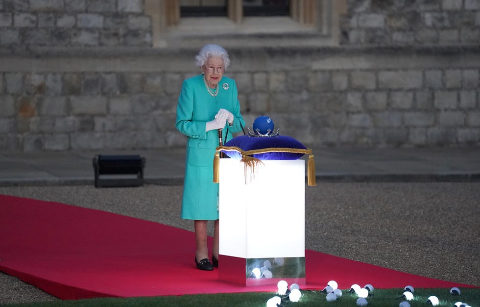 windsor, england   june 02 britains queen elizabeth ii prepares to touch the commonwealth nations globe to start the lighting of the principal beacon outside of buckingham palace in london, from the quadrangle at windsor castle in windsor, west of london, as part of platinum jubilee celebrations on june 2, 2022 in windsor, england more than 2,800 beacons are lit at buckingham palace and across the uk, including atop the four highest peaks, as well as on the channel islands, the isle of man, and british overseas territories flaming tributes will be seen in 54 commonwealth capitals across five continents, from tonga and samoa in the south pacific to belize in the caribbean the platinum jubilee of elizabeth ii is being celebrated from june 2 to june 5, 2022, in the uk and commonwealth to mark the 70th anniversary of the accession of queen elizabeth ii on 6 february 1952 photo by  steve parsons poolgetty images