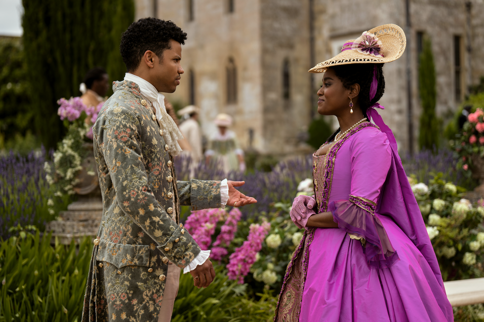 tunji kasim as adolphus and arsema thomas as young agatha danbury conversing in a garden in episode 106 of queen charlotte