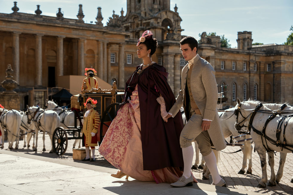 india amarteifio as young queen charlotte and corey mylchreest as young king george walking up stairs in episode 106 of queen charlotte