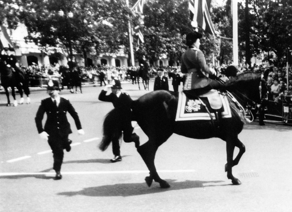 Queen Elizabeth II calms her horse while policemen spring to action after shots were heard as she rode down the mall
