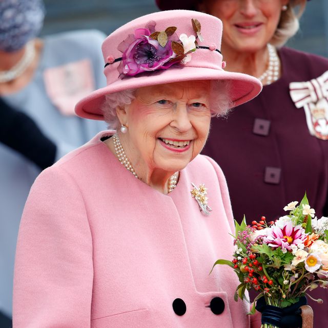queen elizabeth ii in a pink suit holding a bouquet of flowers