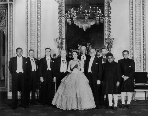 queen with group inside buckingham palace, wearing gown and tiara