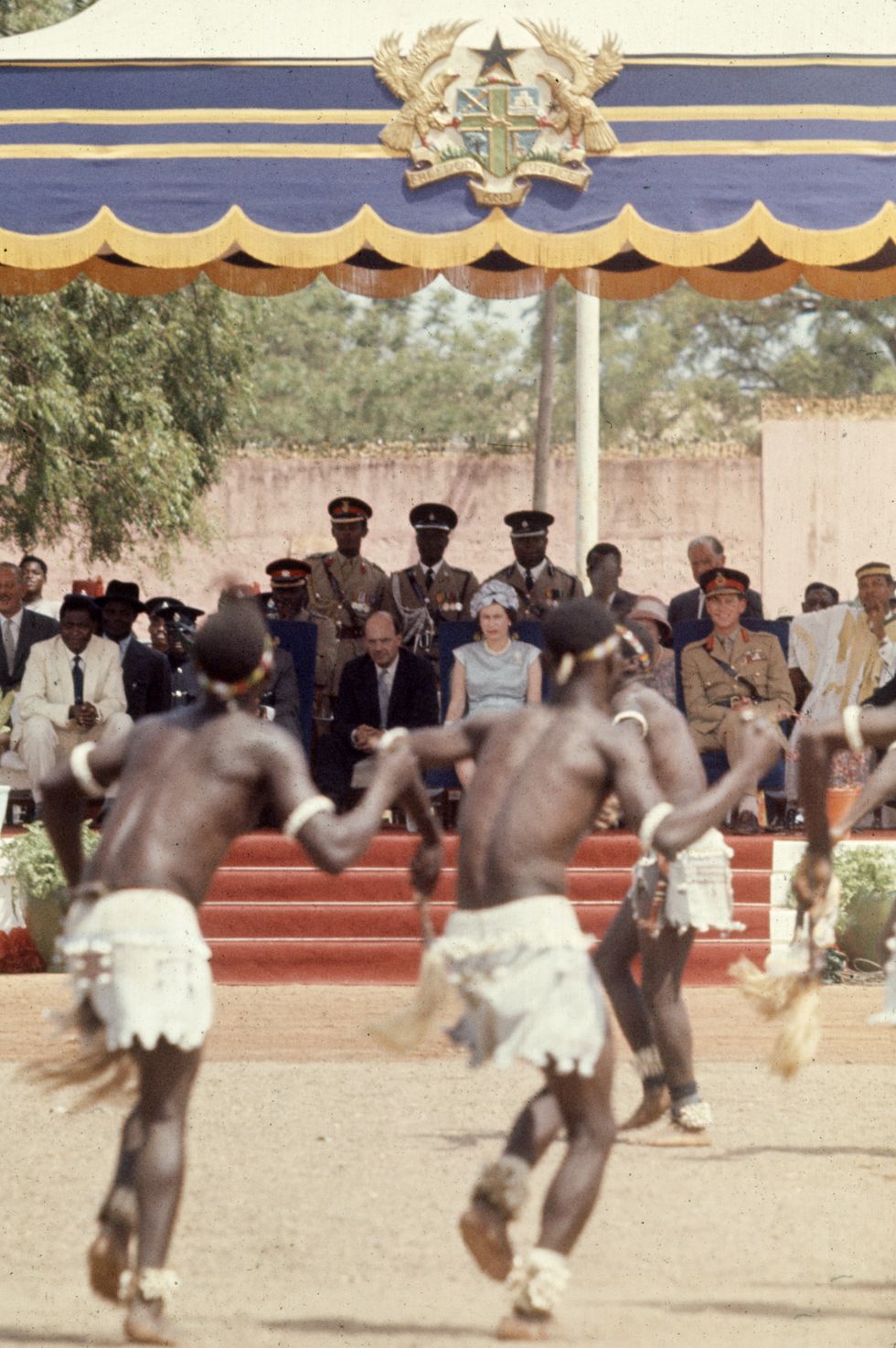 Queen Elizabeth II watches a dance performance in an outdoor parade ground, Tamale, Ghana, November 12, 1961