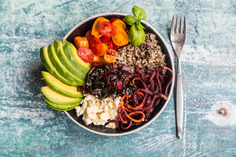 Lunch bowl of quinoa tricolore, chard, avocado, carrot spaghetti, tomatoes and feta