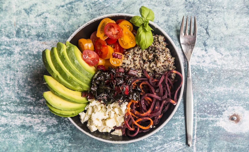 Lunch bowl of quinoa tricolore, chard, avocado, carrot spaghetti, tomatoes and feta