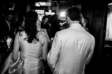 couple in formal attire in a crowded setting facing away from the camera