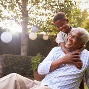 young black boy embracing grandfather sitting in garden