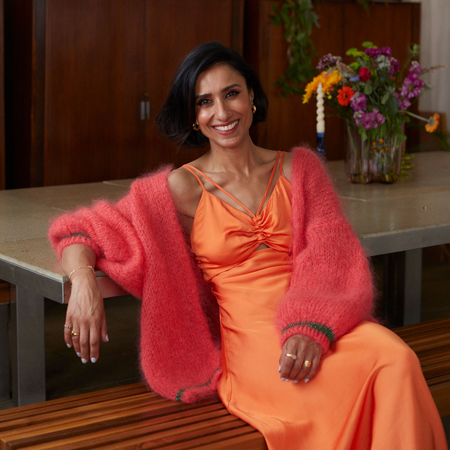 anira rani wears an orange dress and pink cardigan as she smiles into the camera, talking about midlife