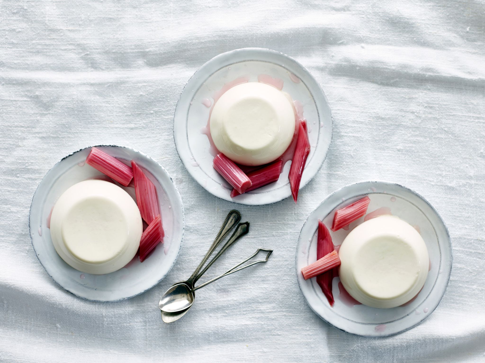 Overhead view of panna cotta desserts with rhubarb on saucers