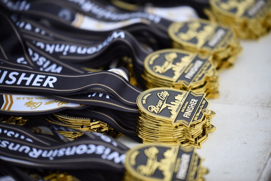 medals with black ribbons labeled finisher and a skyline design brew city half marathon