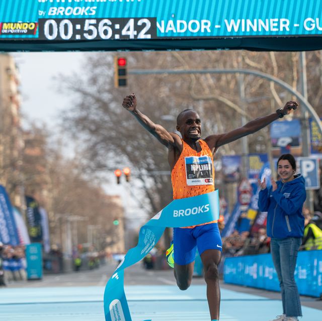 a runner celebrates as he breaks the tape at the end of a race