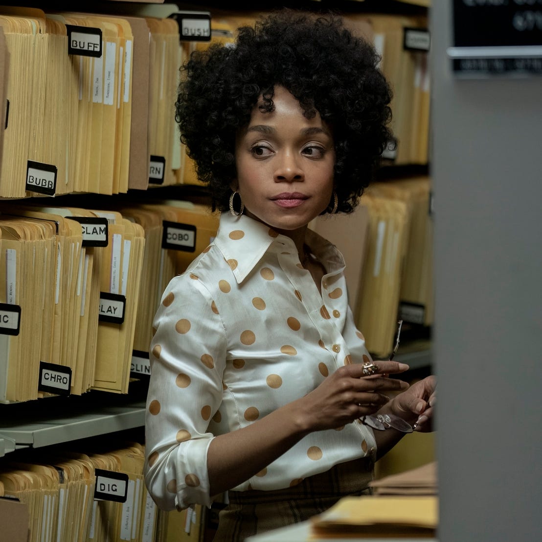 Rachel Hilson in 'Duster' a woman stands among file folders on shelves as she looks to the right