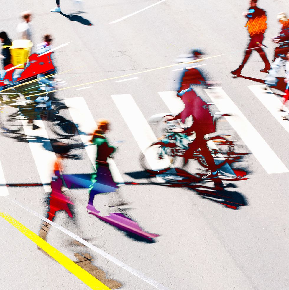 a blurred image of people crossing the road by foot and on bike
