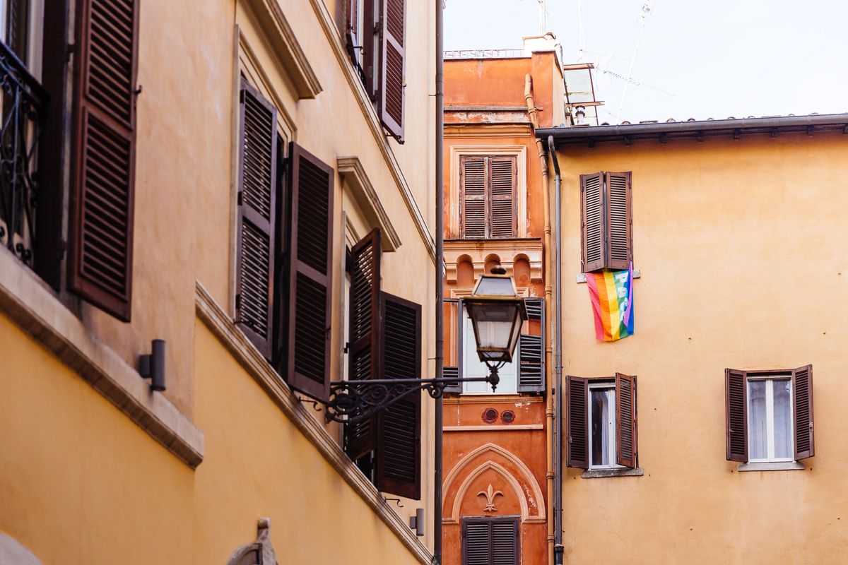 rainbow flag hanging from the window of the residential building in rome, italy
